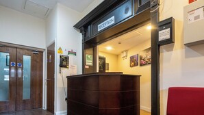 A reception area with a sign above the door, a first aid sign, and a no smoking sign on the wall. - Trivelles Seaforth (Liverpool)