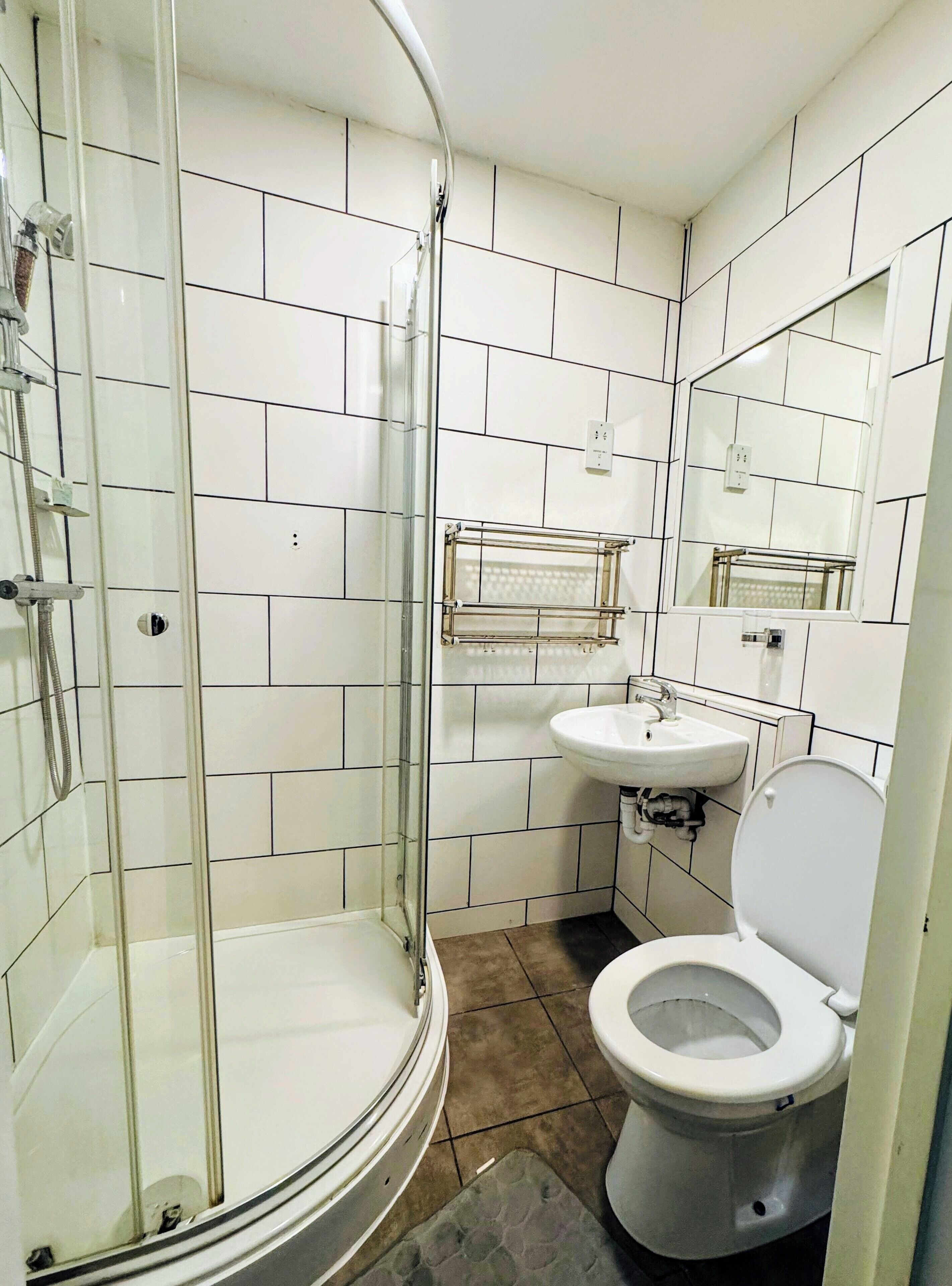A bathroom with a glass-enclosed shower, a sink, and a toilet.
