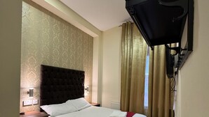 A hotel room with a large bed, a bedside table, a desk, and a wall-mounted TV. - Trivelles Seaforth (Liverpool)