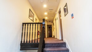 A staircase with a black balustrade leading to a door marked "207". - Trivelles Seaforth (Liverpool)