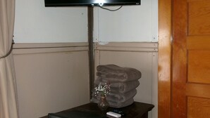 A room with a wooden cabinet, a television mounted on the wall, a radiator, and a wooden door. - Hotel Eastin (Kremmling)