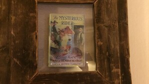 A framed book titled "The Mysterious Rider" by Zane Grey, established in 1817. - Hotel Eastin (Kremmling)