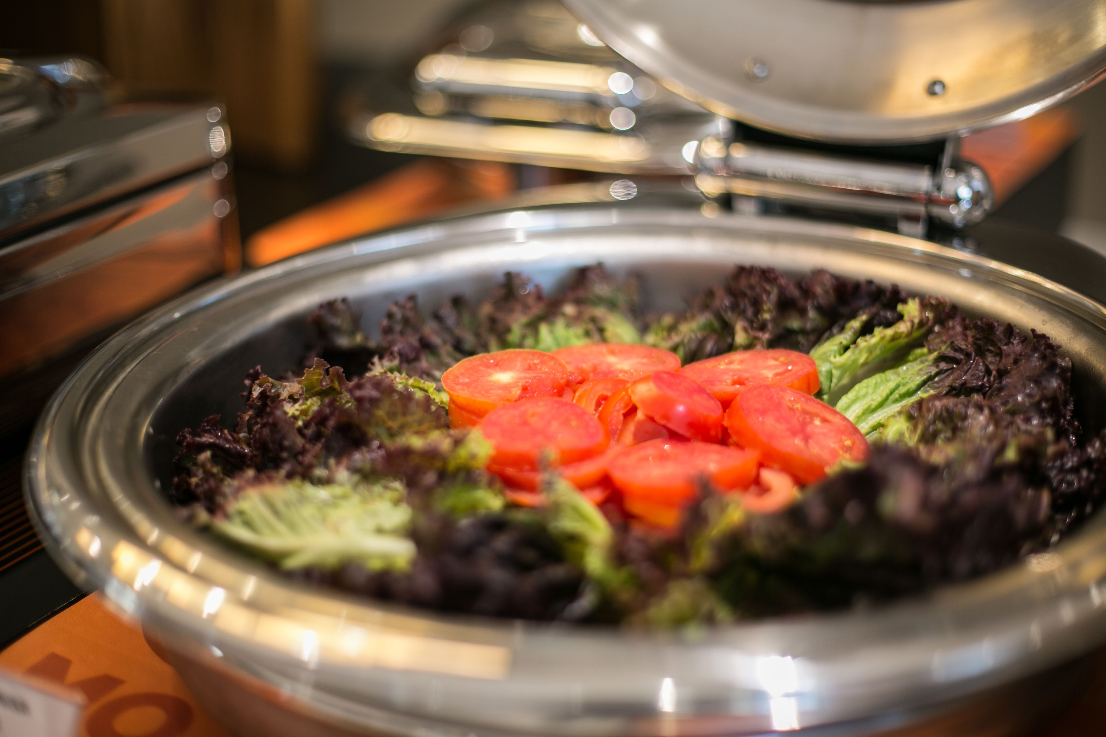 A salad bowl with various greens and sliced tomatoes.