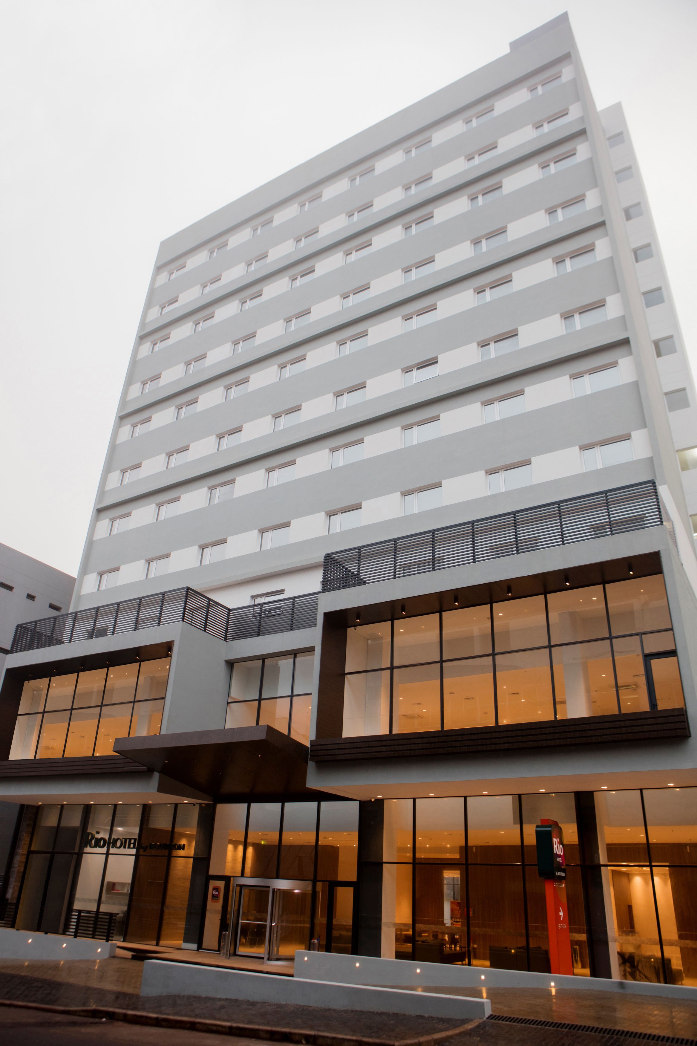 A modern hotel with multiple floors, large windows, and a prominent entrance with a glass door.