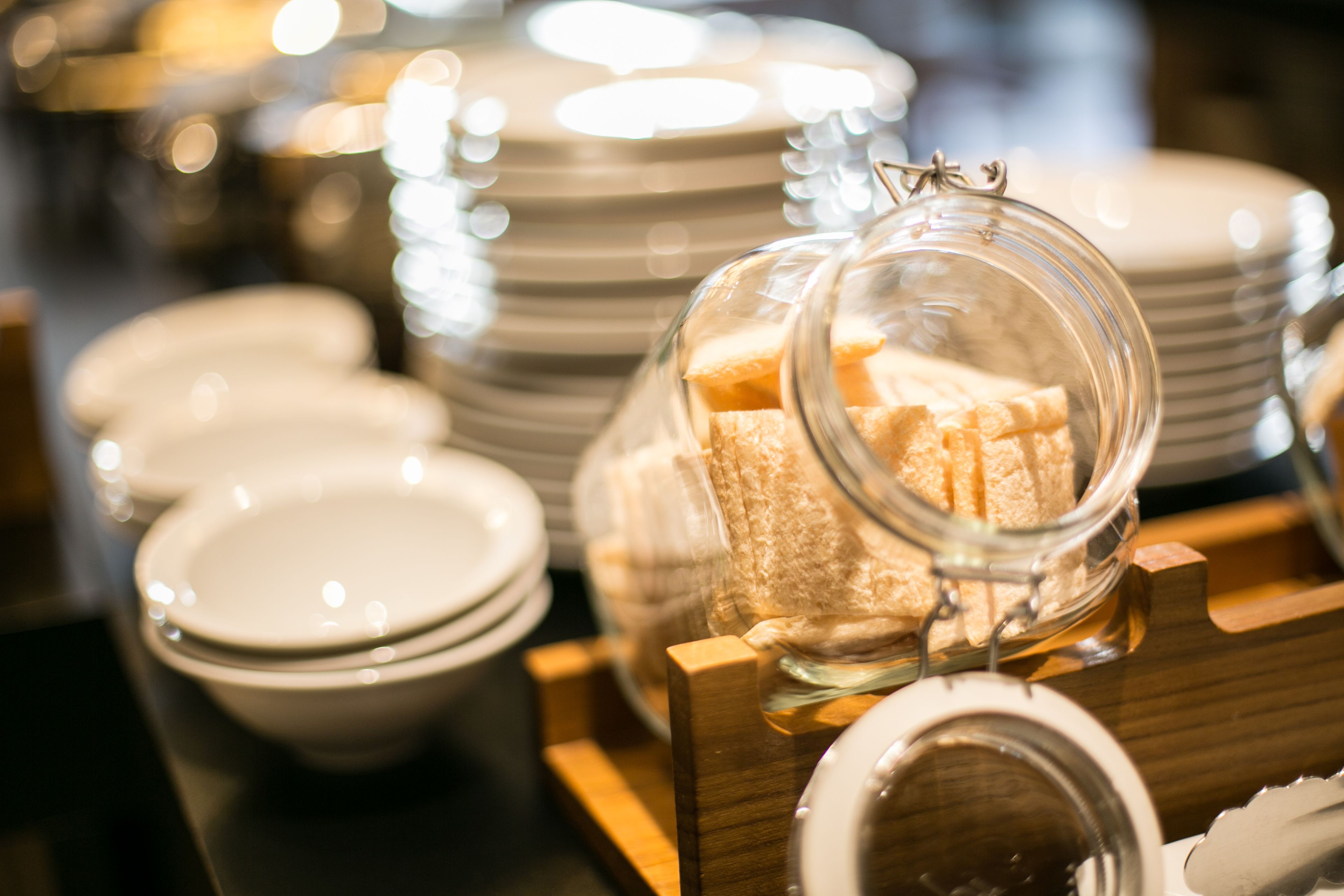 A display of white plates and a glass jar with bread.