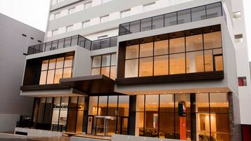 A modern hotel with a glass facade, multiple floors, and a prominent entrance with a revolving door.