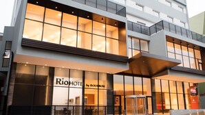 Un hotel modern amb grans finestres, una entrada destacada i un cartell que diu "Rio Hotel by Bourbon".