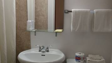 Un baño con lavamanos pedestal, inodoro, toallero y espejo.
