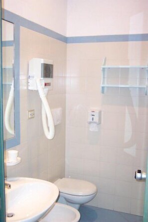 A bathroom with a toilet, sink, and shower area.