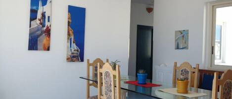 Ein Essbereich mit einem Glastisch, Holzstühlen und zwei Bildern an der Wand.