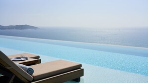 Una piscina infinita con vistas al mar y una isla en la distancia.