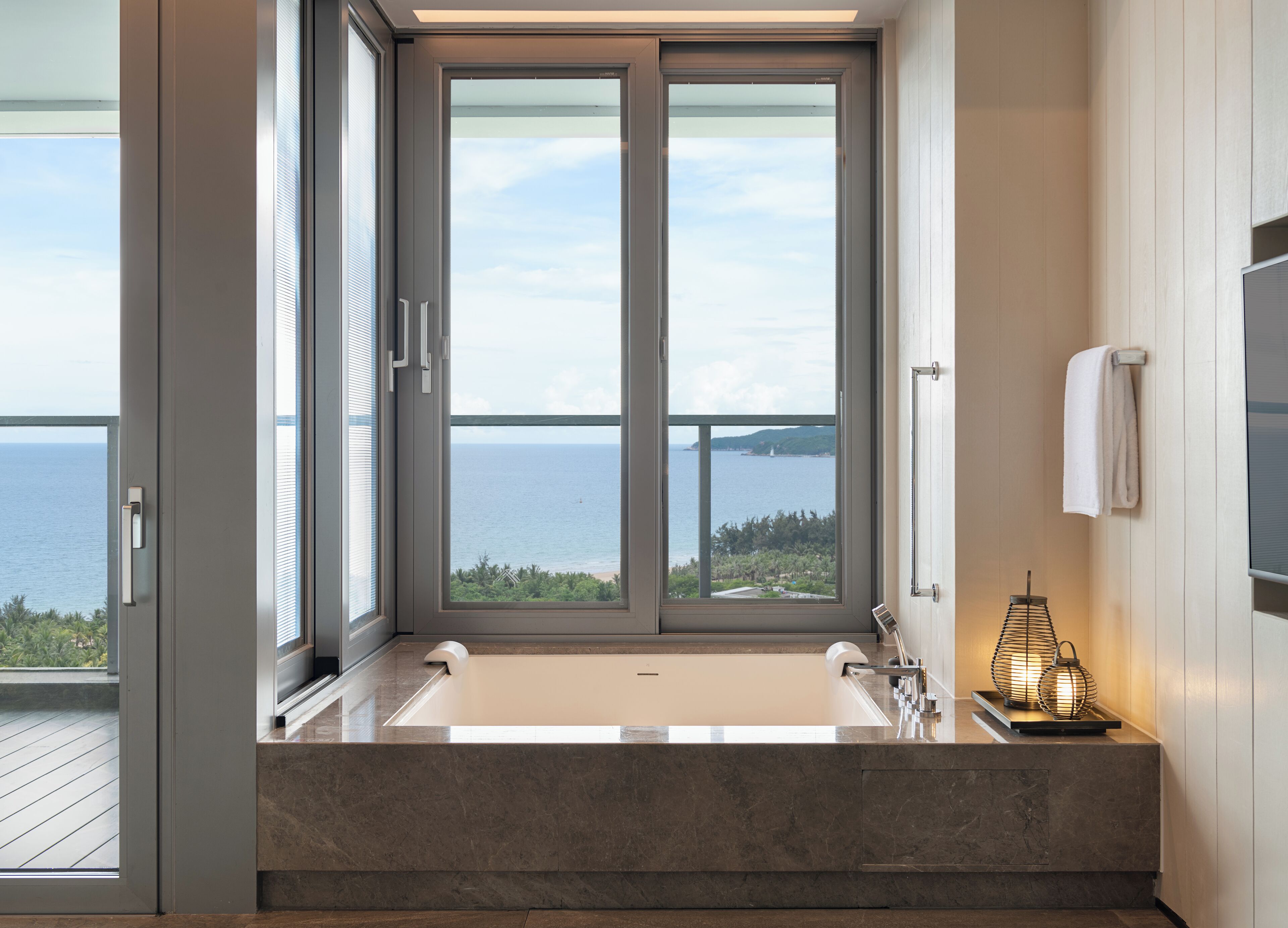 A modern bathroom with a large window, a bathtub, and a towel rack.