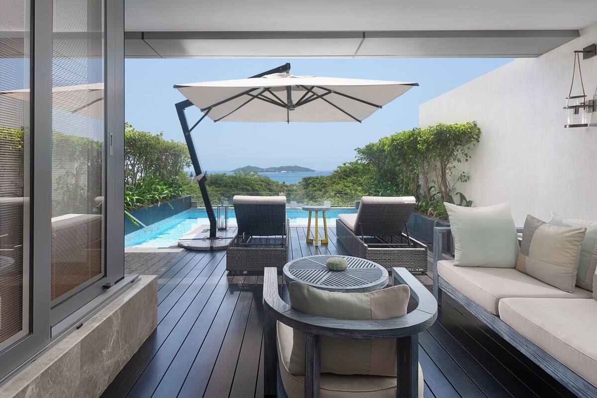 Una terraza con mobiliario exterior, una piscina y vistas al mar.
