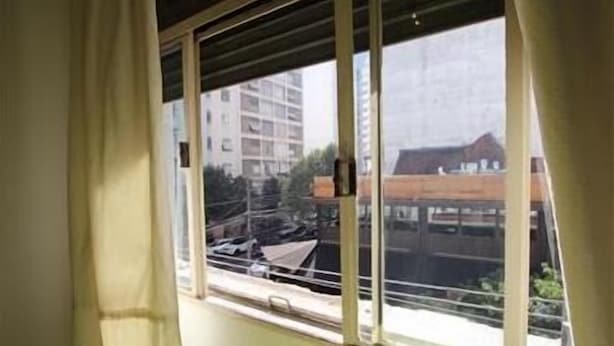 Une fenêtre donnant sur un immeuble et quelques arbres.