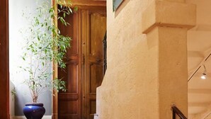 Una escalera con peldaños rojos que conduce a una puerta de madera, una planta en maceta y un cuadro en la pared.