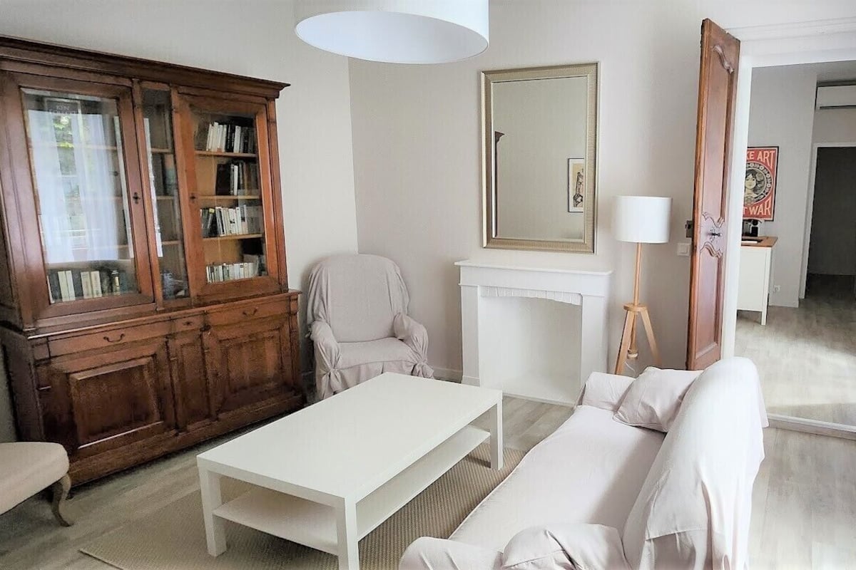 A living room with a white sofa, a white coffee table, a wooden cabinet, and a mirror on the wall.
