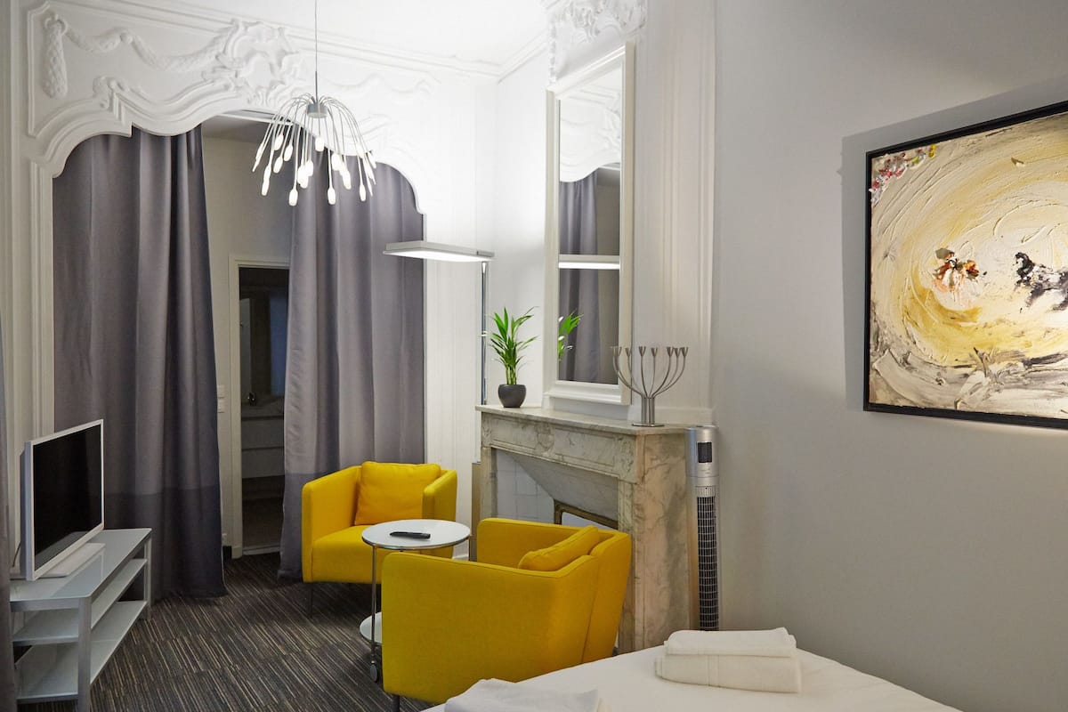 A hotel room with a modern design, featuring a fireplace, a television, and a comfortable seating area with yellow chairs.