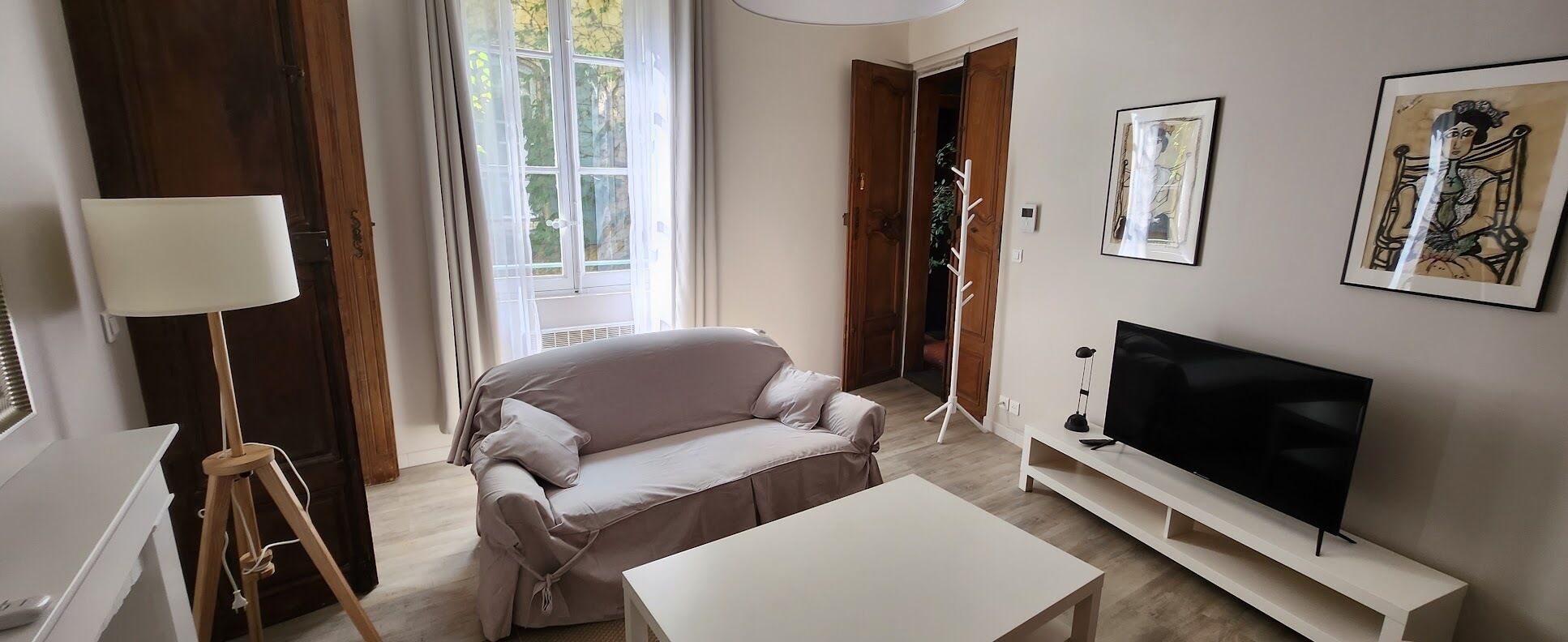 A living room with a sofa, a TV, a lamp, and a window.