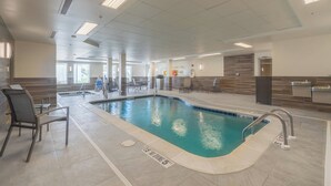 A swimming pool with a 5 ft depth marker, surrounded by lounge chairs and a sunlit indoor area with a tiled floor and a wooden accent wall. - Fairfield Inn & Suites by Marriott Gaylord (Gaylord)