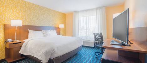 A hotel room with a bed, bedside lamps, a desk with a TV, and a window with curtains.