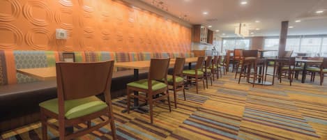A restaurant with booths and tables, a patterned carpet, and a wall with circular designs.
