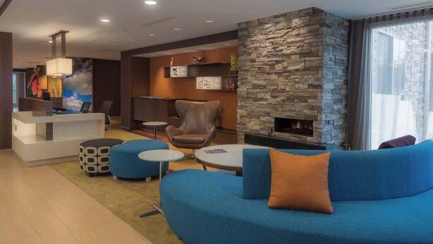 A modern lounge area with a stone fireplace, blue seating, and a reception desk. - Fairfield Inn & Suites by Marriott Gaylord (Gaylord)