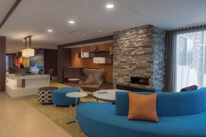 A modern lounge area with a stone fireplace, blue seating, and a reception desk. - Fairfield Inn & Suites by Marriott Gaylord (Gaylord)