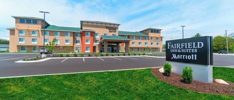Un hotel Fairfield Inn & Suites Marriott con estacionamiento y un área verde al frente.
