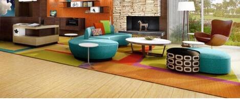 A modern living room with a stone fireplace, a blue sofa, a round coffee table, and a wooden reception desk.