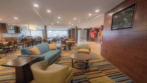 A hotel lobby with a sofa, armchairs, a coffee table, and a TV mounted on the wall. - Fairfield Inn & Suites by Marriott Gaylord (Gaylord)