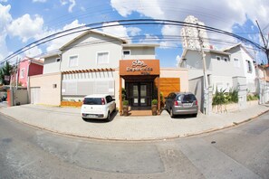 A hotel with a modern facade, a gated entrance, and two parked cars. - Hotel Esplanada (Campinas)