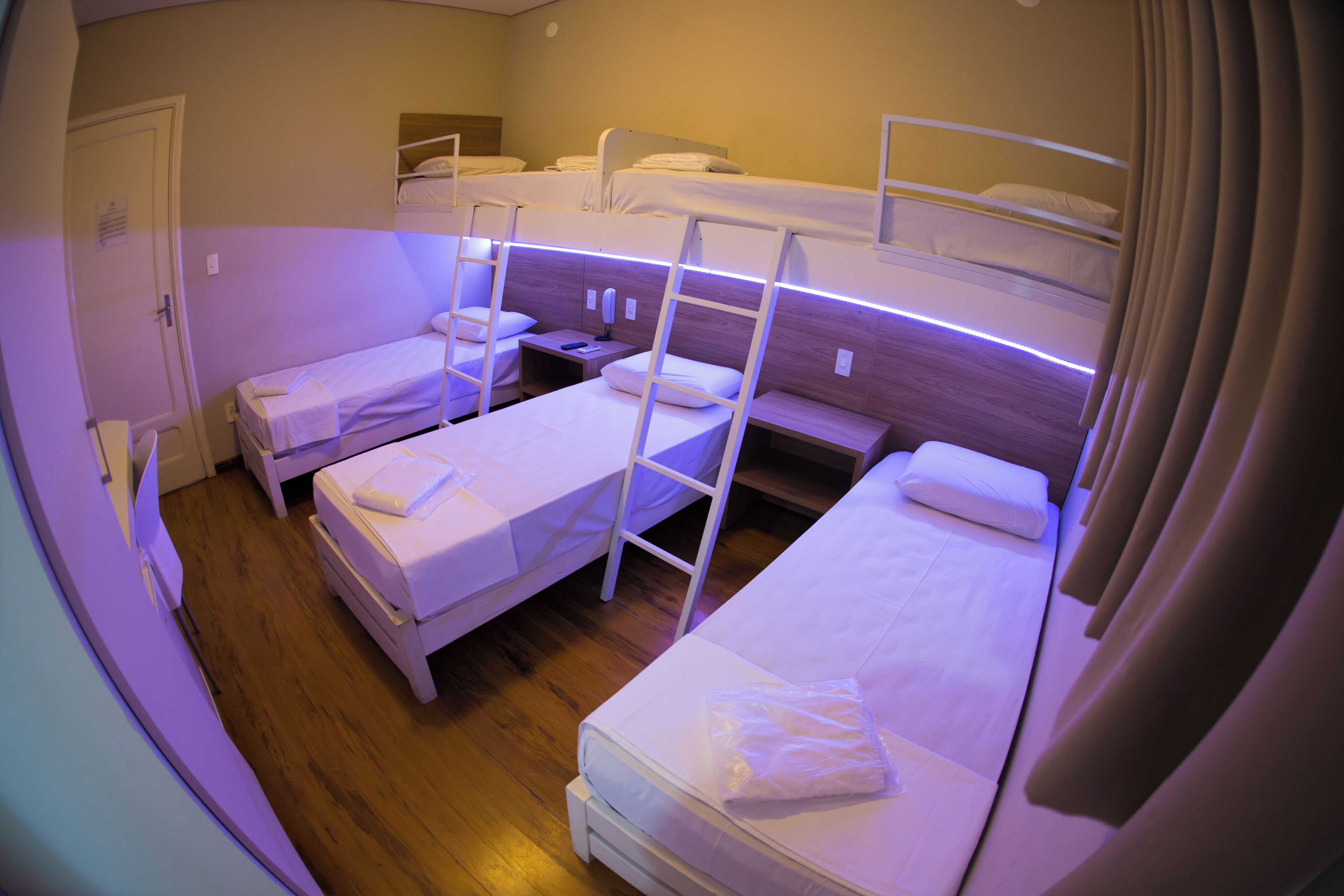 A dormitory room with bunk beds, a bedside table, and a nightstand.