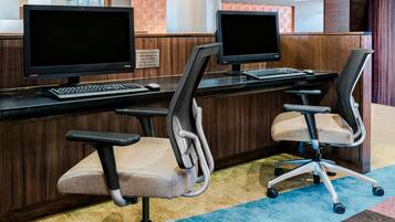 Zona de recepción de un hotel con dos monitores de computadora, un teclado y sillas de oficina.