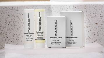 Four Paul Mitchell product boxes on a white shelf against a speckled wall.