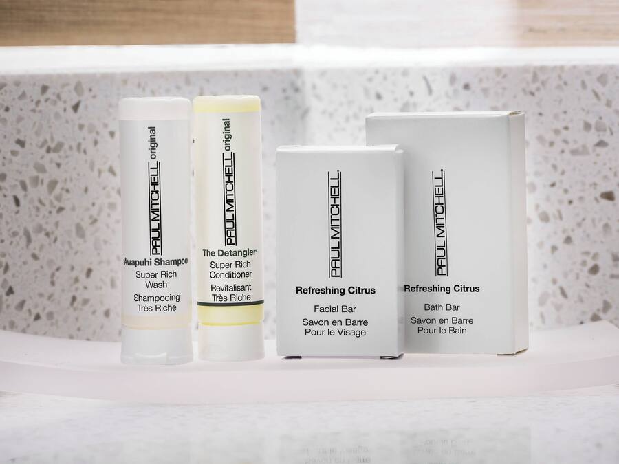 Four Paul Mitchell product boxes on a white shelf against a speckled wall.