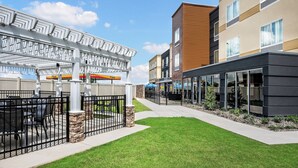 Un bâtiment moderne doté d’un patio couvert, d’un chemin et d’une pelouse bien entretenue.
