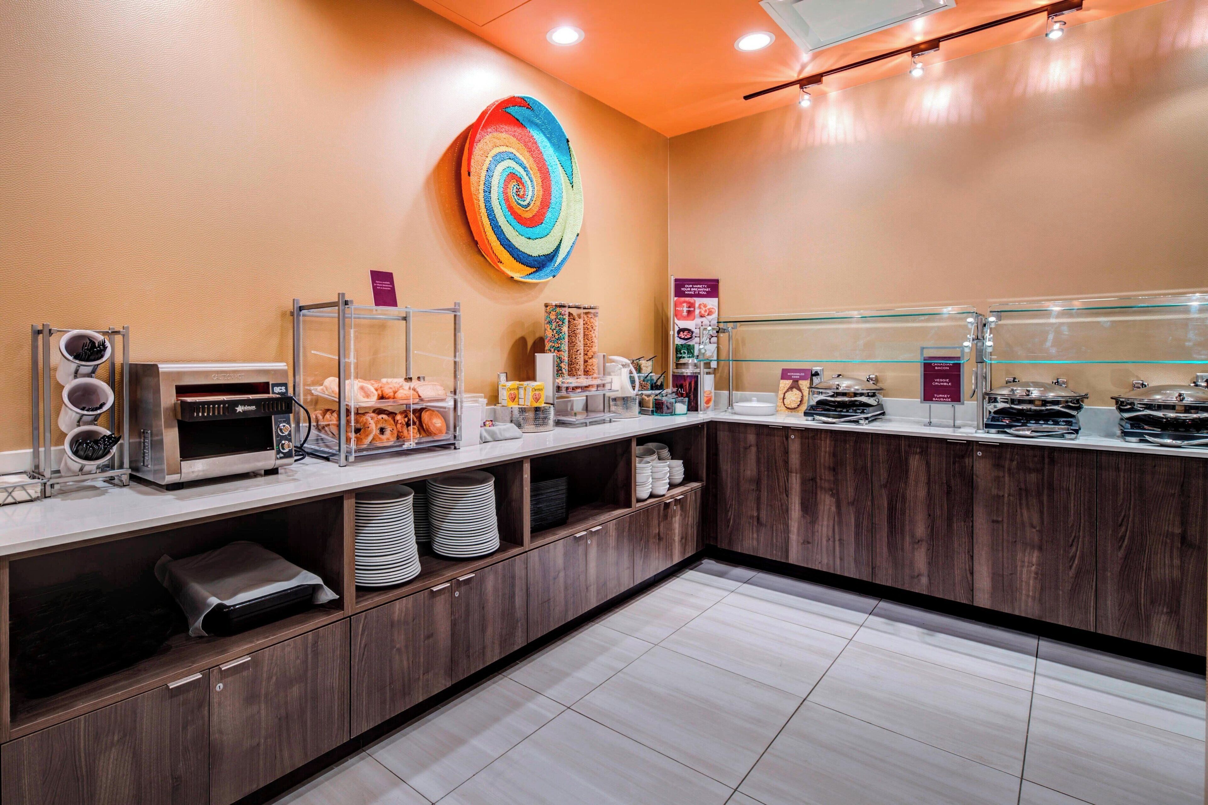 Un buffet allestito con diversi cibi, una macchina per il caffè e una decorazione murale colorata.