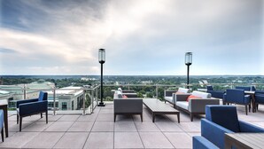 Une terrasse sur le toit, aménagée avec des meubles d’extérieur, notamment des canapés et des fauteuils, ainsi que deux lampadaires.