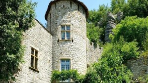 Un edificio de piedra con una torre, ventanas y vegetación circundante.