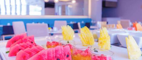 A buffet table with watermelon slices and fruit cups.