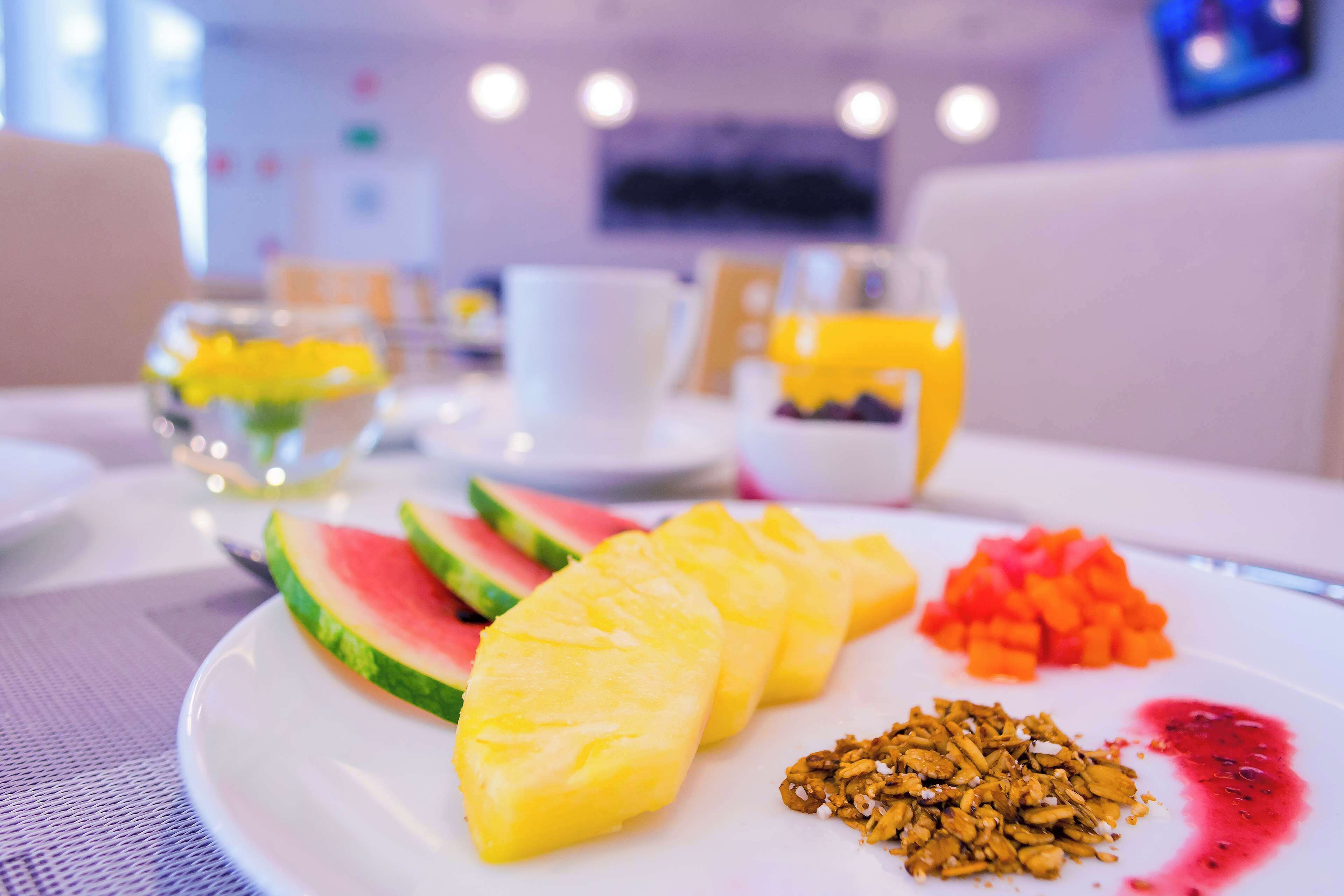 A breakfast plate with watermelon, pineapple, granola, and a fruit compote.