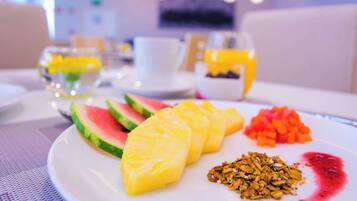 A breakfast plate with watermelon, pineapple, granola, and a fruit compote.