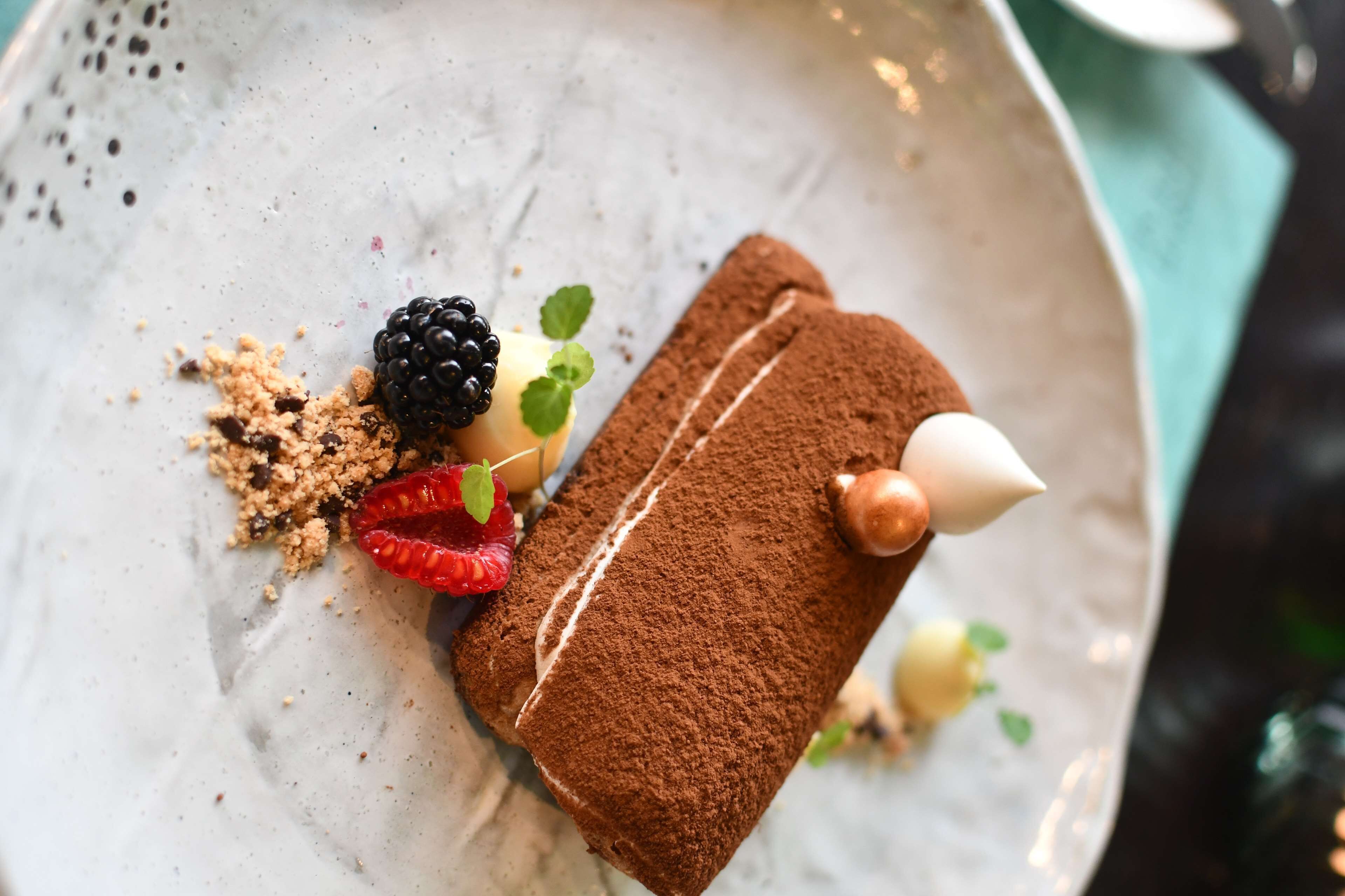Dessert op een bord met chocoladepoeder, bessen en muntblaadjes.