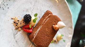 Dessert auf einem Teller mit Kakaopulver, Brombeeren, Himbeeren und Minzblättern.