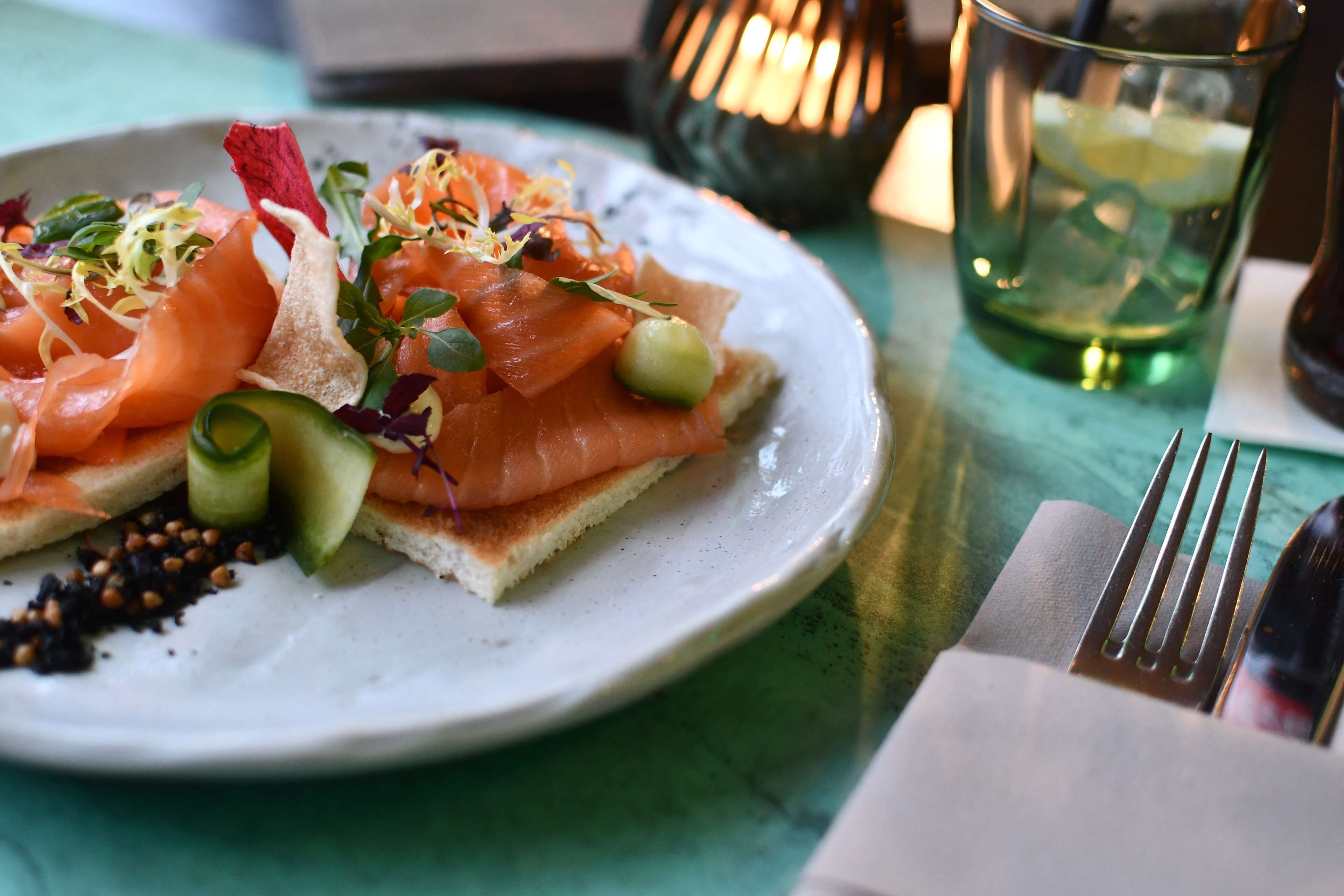 Ein Teller mit Räucherlachs, Avocado und Grünzeug.