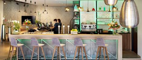A modern bar area with a bar counter, seating, and a television screen.
