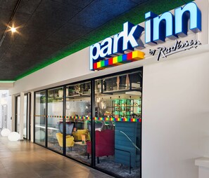 A Park Inn hotel with a modern design, featuring a large illuminated sign, glass walls, and a variety of seating options inside. - Park Inn by Radisson Hasselt (Hasselt)