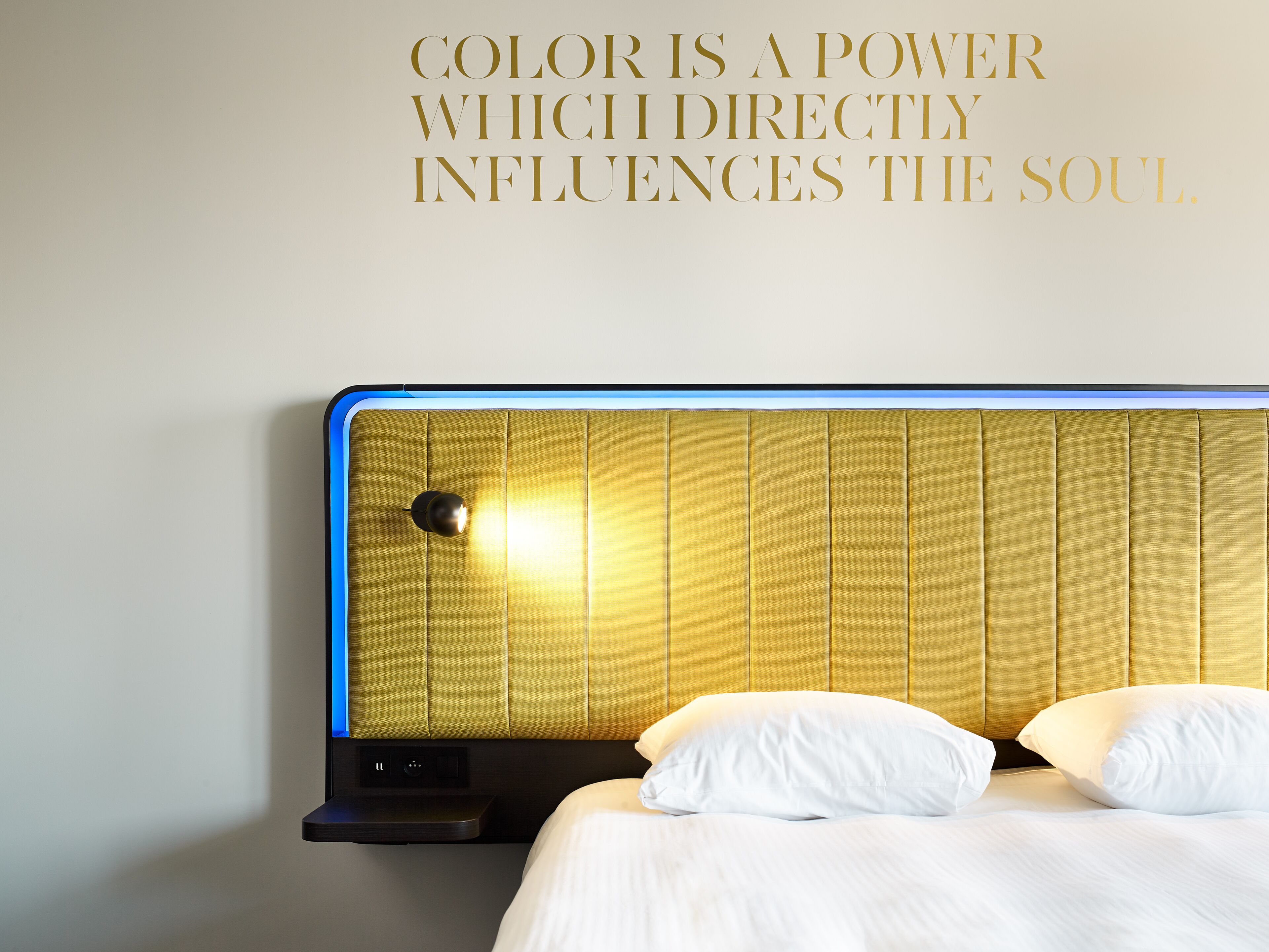 Una cama con ropa blanca y un cabecero con detalles azules.