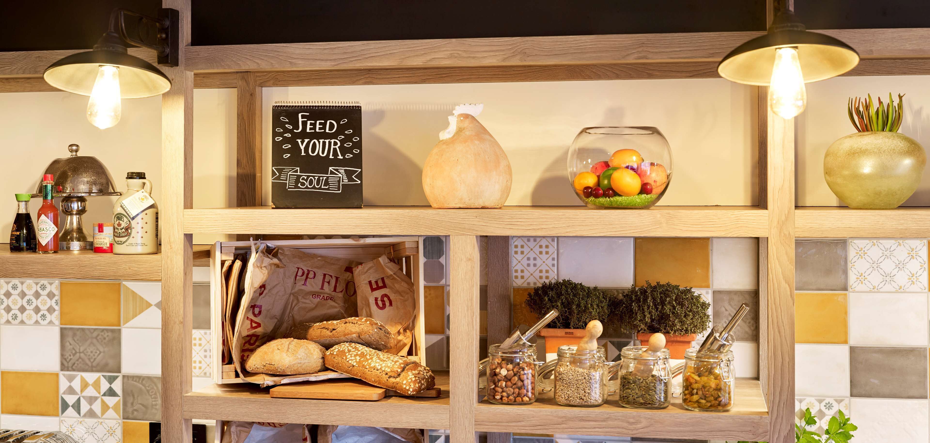 A kitchen counter with a sign that reads "Feed Your Soul," a bowl of fruit, a loaf of bread, and various jars of spices.