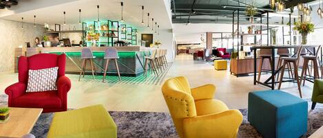 A modern hotel lobby with a bar area, seating arrangements, and a reception desk.